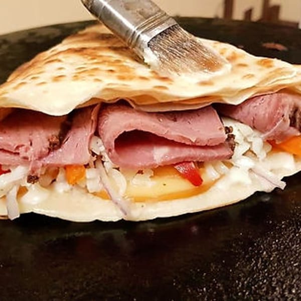 Savory Crepery crepe filled with sliced meat, cheese, and vegetables, brushed with sauce.